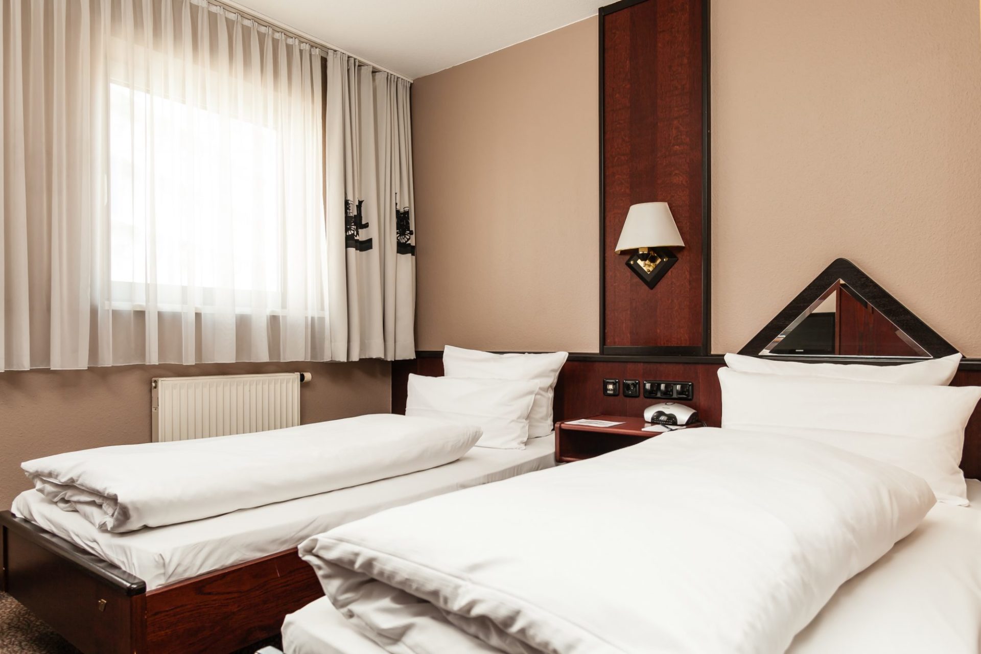 Ein helles Hotelzimmer mit zwei Betten und edelen Holzmöbeln im Best Western Nürnberg